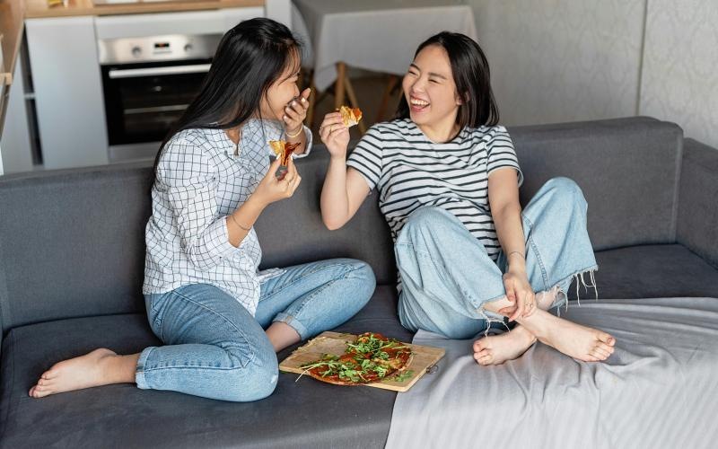 a couple of women eating pizza