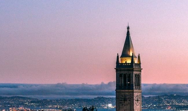 a tall building with a lit up top and a blue sky