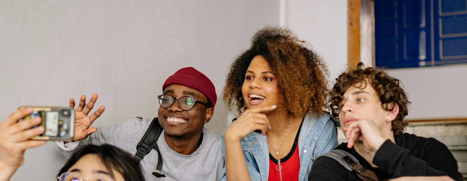 Four young adults hanging out on a sofa taking a photo